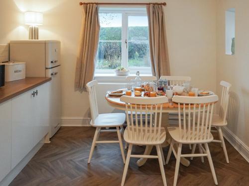 a kitchen and dining room with a table and chairs at Corbetts Lodge Cottage in Swaffham