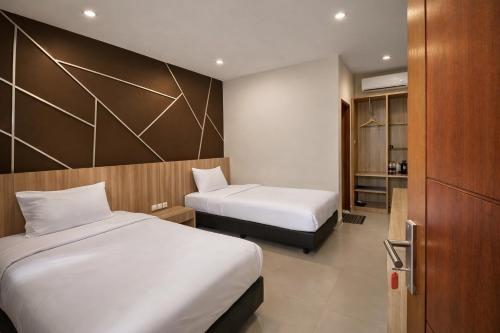 a hotel room with two beds and a closet at Grand Kuta Hotel Lombok - Pool - 43 inch Google TV - Strong 60Mbps WiFi - New Enhanced Management in Kuta Lombok