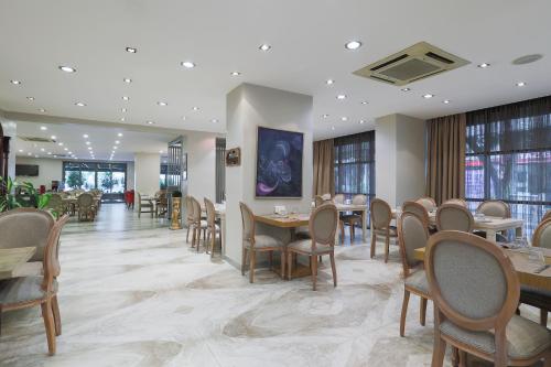 a dining room with tables and chairs and windows at Nobel Hotel in Mersin