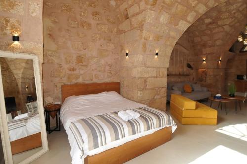 a bedroom with a bed and a stone wall at Dar22 in Fad‘ūs