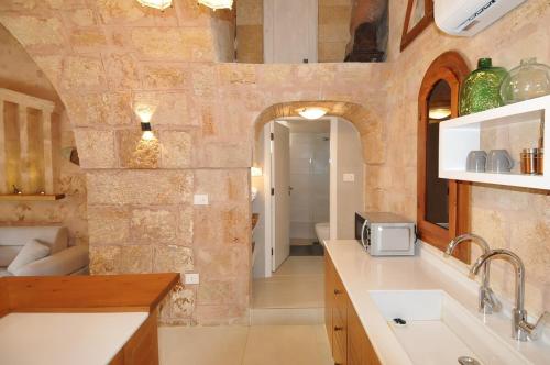 a kitchen with a stone wall and a sink at Dar22 in Fad‘ūs