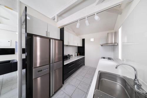 a kitchen with a stainless steel refrigerator and a sink at Powdersuites in Hakuba