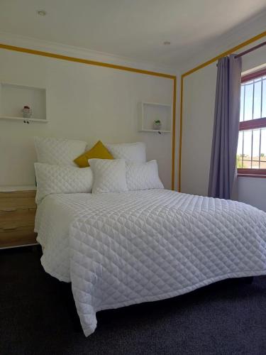 a bedroom with a large white bed with a window at Capetown Adilo Villa 2 in Cape Town