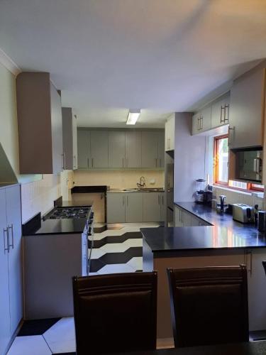 a large kitchen with white cabinets and black counter tops at Capetown Adilo Villa 2 in Cape Town