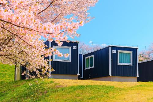 a house with a flowering tree in front of it at MOBILITA COURT IWATE in Hachimantai