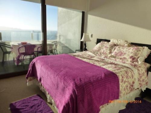 a bedroom with a purple bed and a balcony at Departamento La Serena in Coquimbo