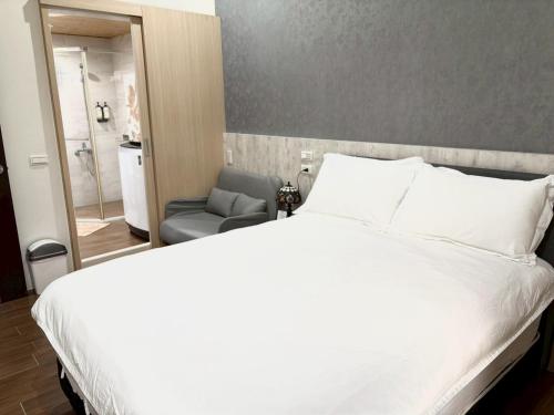 a bedroom with a white bed and a chair at Happiness B&B in Linbian