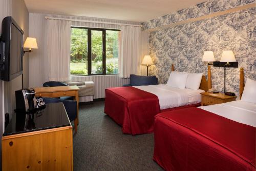 a hotel room with two beds and a television at Williamsburg Woodlands Hotel & Suites, an official Colonial Williamsburg Hotel in Williamsburg