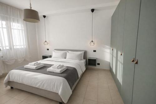 a white bedroom with a large bed with two towels at Appartamento L'Olivo in Latina