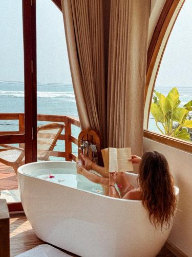 a woman sitting in a bath tub reading a book at Ocean Bliss by Sugar Coliving in Weligama
