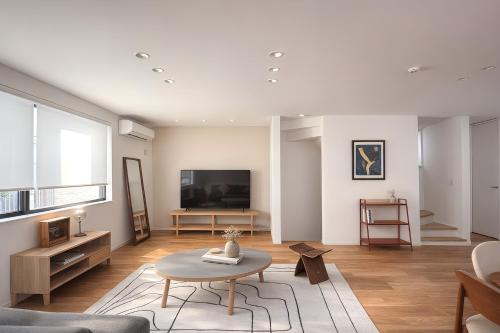 a living room with a table and a tv at USJ 梅田 大阪城へ直通 駐車場付きモダン一軒家 JR弁天町駅3分 LIRI Kasumi in Osaka