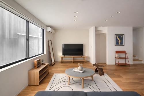 a living room with a tv and a table at USJ 梅田 大阪城へ直通 駐車場付きモダン一軒家 JR弁天町駅3分 LIRI Kasumi in Osaka