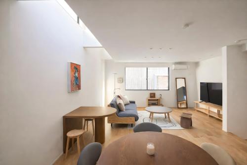 a living room with a table and a couch at USJ 梅田 大阪城へ直通 駐車場付きモダン一軒家 JR弁天町駅3分 LIRI Kasumi in Osaka