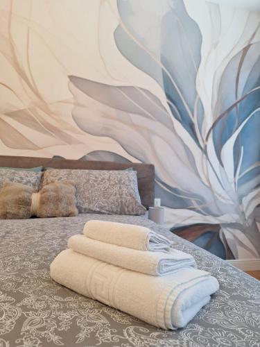 a bed with three towels on it with a mural at Affittacamere La Polse in Osoppo