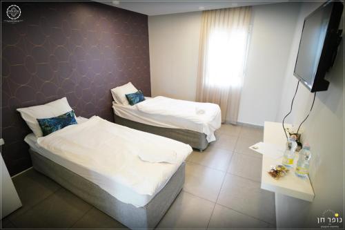 a hotel room with two beds and a flat screen tv at El Yam in Netanya