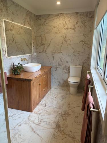 a bathroom with a sink and a toilet at Pouto Farms Packhouse - Coastal Farmhouse in Pouto