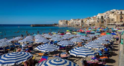 plaża z wieloma błękitnymi i białymi parasolami w obiekcie Porto Salvo Apartments - by Vacation Service w Cefalù