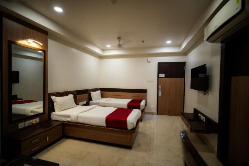 a bedroom with two beds and a mirror and a television at Hotel Gharana Tree in Gaya