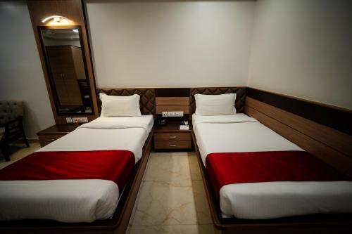 two beds in a hotel room with red sheets at Hotel Gharana Tree in Gaya