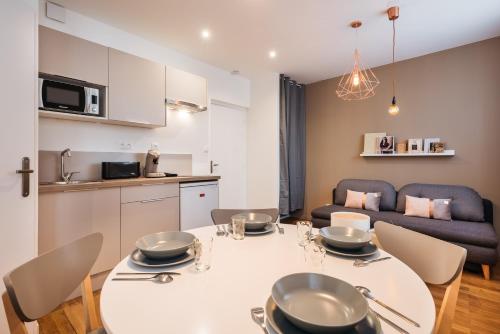 里昂的住宿－Studios Part-Dieu Gare - HomaLyon，厨房以及带白色桌椅的起居室。