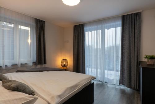 a bedroom with two beds and large windows at Apartmány Sunny hill in Frymburk