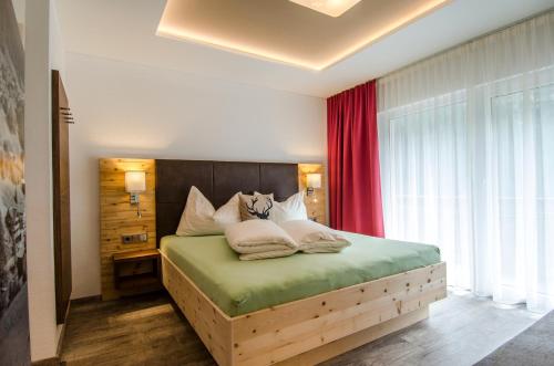 1 dormitorio con cama de madera y cortina roja en Garni Montana, en Kappl