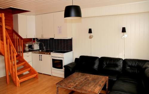 a living room with a black leather couch and a table at Havøysund Hotell & Rorbuer in Havøysund