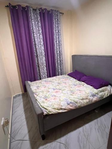 a bed in a room with purple curtains at The Mountain Gaze in Nyeri