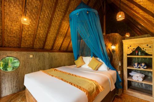 a bedroom with a bed with a blue canopy at Vana Nugraha Villas in Tampaksiring