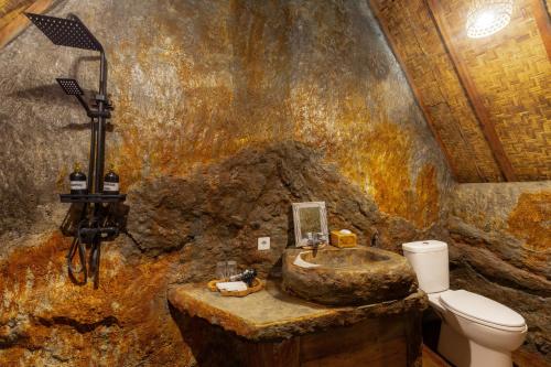 a stone bathroom with a sink and a toilet at Vana Nugraha Villas in Tampaksiring
