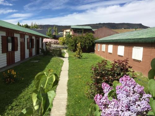 a view of a yard with flowers and buildings at Hostel Los Pioneros in El Calafate