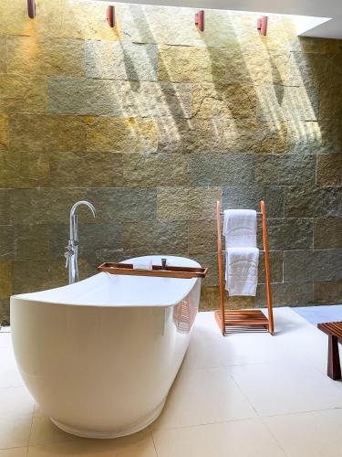 a bath tub in a bathroom with a stone wall at Bluewater Panglao Beach Resort in Panglao Island
