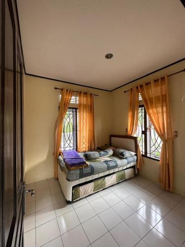 a bedroom with two beds and two windows at Vila Biru Gundaling Brastagi in Berastagi