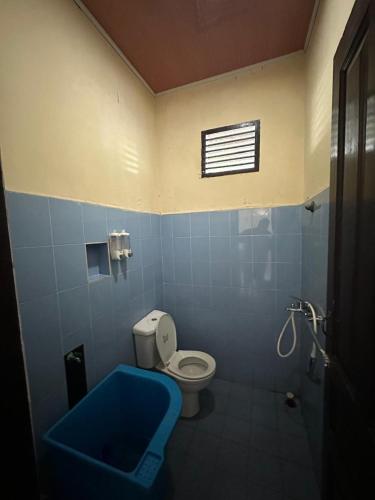 a bathroom with a toilet and a blue tub at Vila Biru Gundaling Brastagi in Berastagi