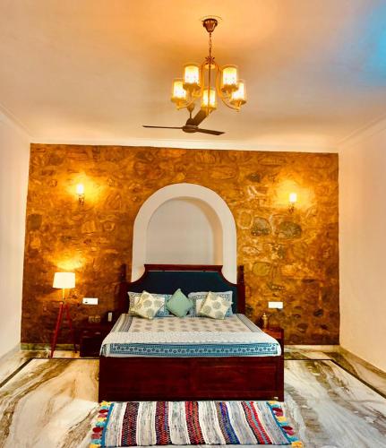 a bedroom with a bed with a stone wall at The WildRocks Jawai in Nāna