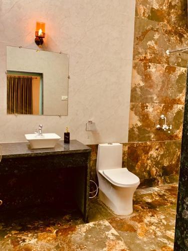 a bathroom with a white toilet and a sink at The WildRocks Jawai in Nāna