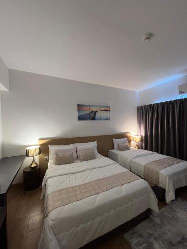 two beds in a hotel room with two lamps at Putra Hotel at Mydin Tunjong in Kota Bharu