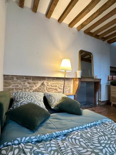 a bed with two pillows and a lamp in a room at Maison cosy à côté de Beaune in Savigny-lès-Beaune