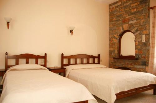 1 dormitorio con 2 camas y pared de piedra en Melifilos, en Agios Ioannis