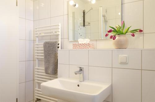 a white bathroom with a sink and a mirror at Eicher Ferienwohnungen Warnemünde in Warnemünde