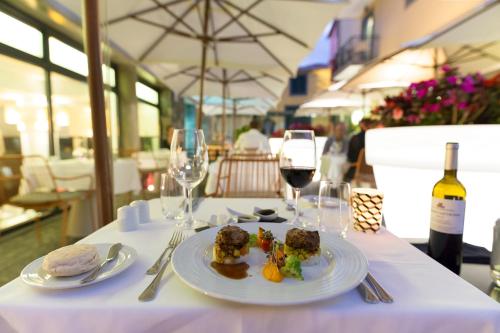a table with a plate of food and glasses of wine at Castanheiro Boutique Hotel in Funchal
