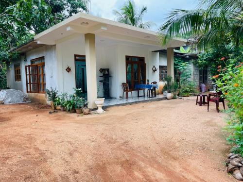 a small white house with a table and chairs at Kumara Guest House Dambulla in Dambulla