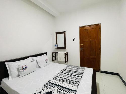 a bedroom with a bed and a wooden door at Kumara Guest House Dambulla in Dambulla