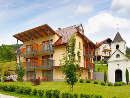 a large house on a hill with a church at Villa Aina Boutique Hotel in Laško