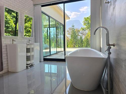 a bathroom with a bath tub and a large window at Sa Prung on the mountain - สะพรั่งกลางขุนเขา in Ban Tham
