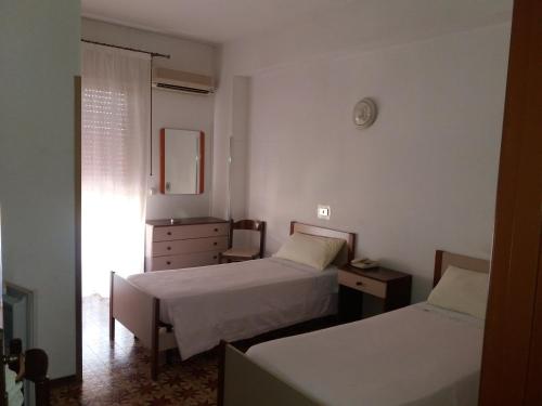 a bedroom with two beds and a dresser and a mirror at Albergo Europa in Vittoria