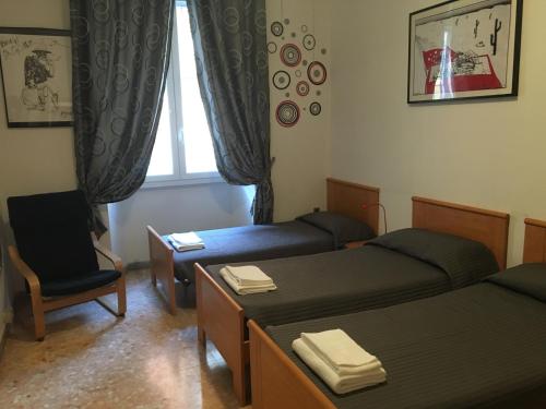 ローマにあるDelightful apartment 100 meters from the Colosseumのベッド2台、椅子、窓が備わる客室です。
