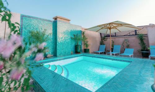 a swimming pool with chairs and an umbrella at Riad El Hara in Marrakesh