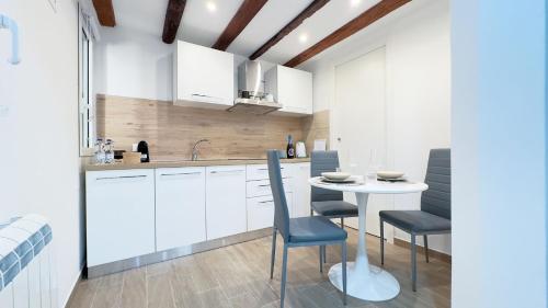 a kitchen with white cabinets and a table and chairs at Maison Studio in Chioggia