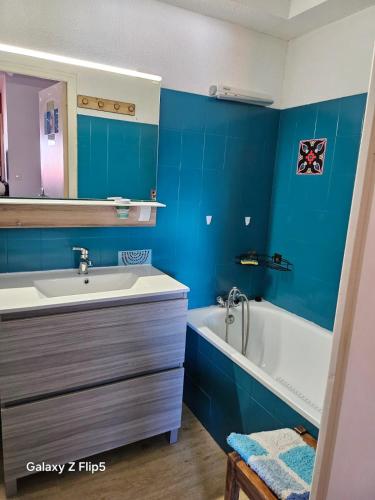 a bathroom with blue walls and a sink and a tub at joli studio vue montagne in Allos